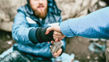 Einem Obdachlosen wird eine Hand gereicht | © AleksandarGeorgiev - Getty Images/iStockphoto